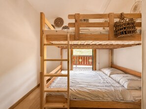 Ein Etagenbett mit Holzleiter, einem gewebten Korb und dekorativen Tellern an der Wand.