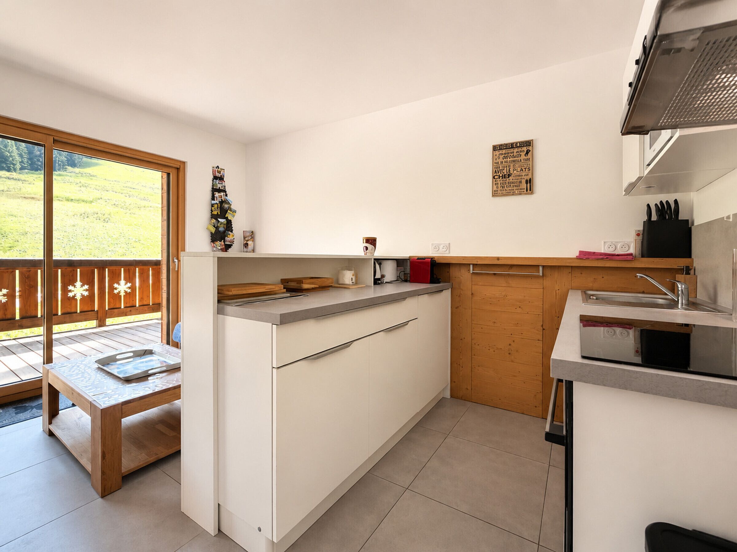 Een moderne keuken met een houten terras, een ingebouwde oven en een spoelbak.
