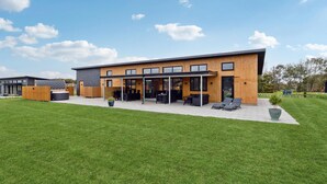 A modern building with a covered patio area, outdoor seating, and a well-maintained lawn. - Gorgeous home in Hadsund with sauna (Hadsund)
