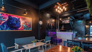 Un interior moderno con un mural grande, muebles de madera y una escalera que lleva a una zona de bar.