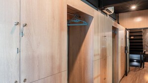 Un pasillo moderno de hotel con taquillas de madera, un perchero azul y una escalera que conduce a un nivel superior.