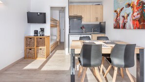 Una cuina moderna amb armaris de fusta, forn integrat i una pica. Hi ha una taula de dinar amb cadires i un quadre al mur.