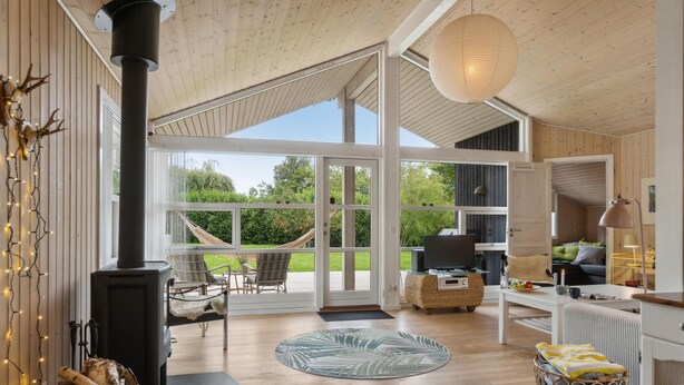 A spacious living area with a large window, a fireplace, and a cozy seating arrangement. - Amazing home in Fårevejle with sauna (Fårevejle)