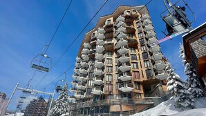 A multi-story hotel with balconies, ski lift cables, and snow-covered trees. - Family apartment for 6 in Avoriaz, direct slope access (Avoriaz)