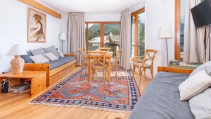 A cozy room with a sofa, a dining table with chairs, a TV, and a large window offering a view of the outdoors. - Family apartment for 6 in Avoriaz, direct slope access (Avoriaz)