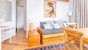 A modern living room with a sofa, wooden dining table, and a painting on the wall. - Family apartment for 6 in Avoriaz, direct slope access (Avoriaz)