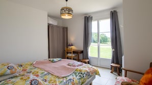 Een slaapkamer met een bed, een bureau en een stoel. Er is een raam met gordijnen en uitzicht op buiten.