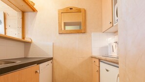 A compact kitchen with wooden cabinets, a built-in dishwasher, and a microwave. - Cozy 2-room south, 5 pers, Avoriaz (Avoriaz)