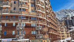 A multi-story hotel with wooden balconies and ski slope views.