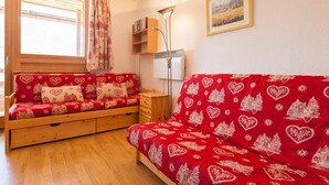 A cozy room with a wooden sofa bed and a matching armchair, both with heart-patterned upholstery.