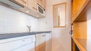 A compact kitchen with a dishwasher, microwave, and wooden cabinets.
