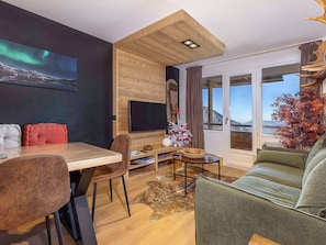 A modern living room with a wooden ceiling, a flat-screen TV, a dining area with a table and chairs, and a sofa. - Spacious 3/4-room apartment for 6 people in Avoriaz (Avoriaz)
