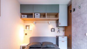 A bedroom with a bed, bedside tables, a wardrobe, and wall-mounted shelves.
