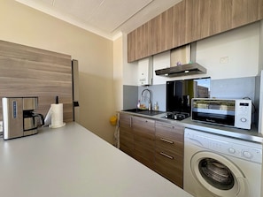 A modern kitchen with a coffee maker, microwave, stove, and washing machine.