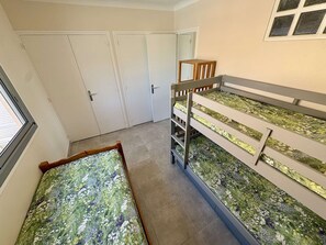 Ein Stockbett mit Blumenmuster, ein Fenster und eine Tür in einem Raum mit Fliesenboden.