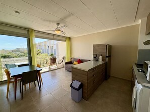 Eine moderne Wohnung mit Balkon, Essbereich, Küchenzeile und einer Couch.