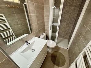 Ein Badezimmer mit einem weißen Waschbecken, einer Toilette und einer Duschkabine.