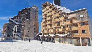 A modern ski resort with multi-story buildings featuring wooden balconies and ski slopes.