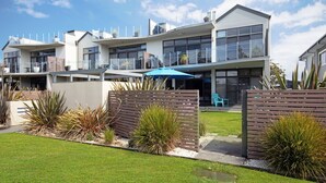 A modern multi-story residential building with a flat roof, large windows, and a well-maintained lawn. - Serenity Shores by Book Jervis Bay (Huskisson)