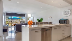 A modern kitchen with a large island, a built-in dishwasher, and a microwave. - Serenity Shores by Book Jervis Bay (Huskisson)