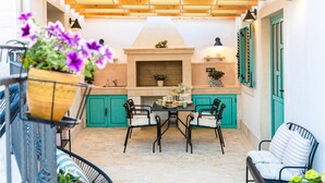 Un área de cocina al aire libre acogedora, con suelo de piedra, techo de madera y muebles de color turquesa.