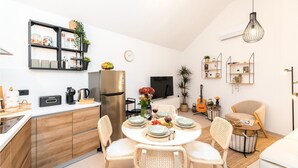 Una cocina moderna con comedor, televisor y guitarra.