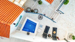 Un área de piscina en la azotea con piscina azul, sillas de descanso y una escalera.