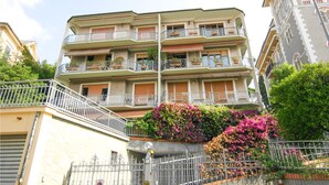 Un immeuble résidentiel à plusieurs étages, doté de balcons, d’un mur en pierre et d’un portail en métal.