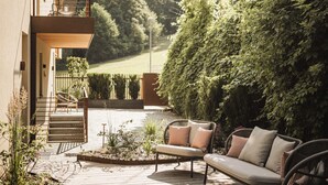 Une terrasse avec mobilier d’extérieur, une plateforme en bois et une vue sur une colline boisée.