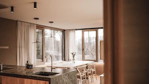 Une cuisine moderne dotée d’un îlot en marbre, de meubles en bois et d’une grande fenêtre qui laisse entrer la lumière naturelle.