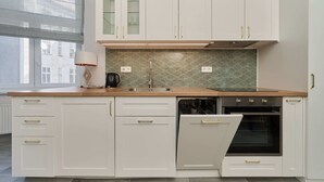 A modern kitchen with white cabinetry, a built-in oven, and a large window providing natural light. - Elegant Apartment in Tenement House | Center, 2 Desks for Work (Poznan)
