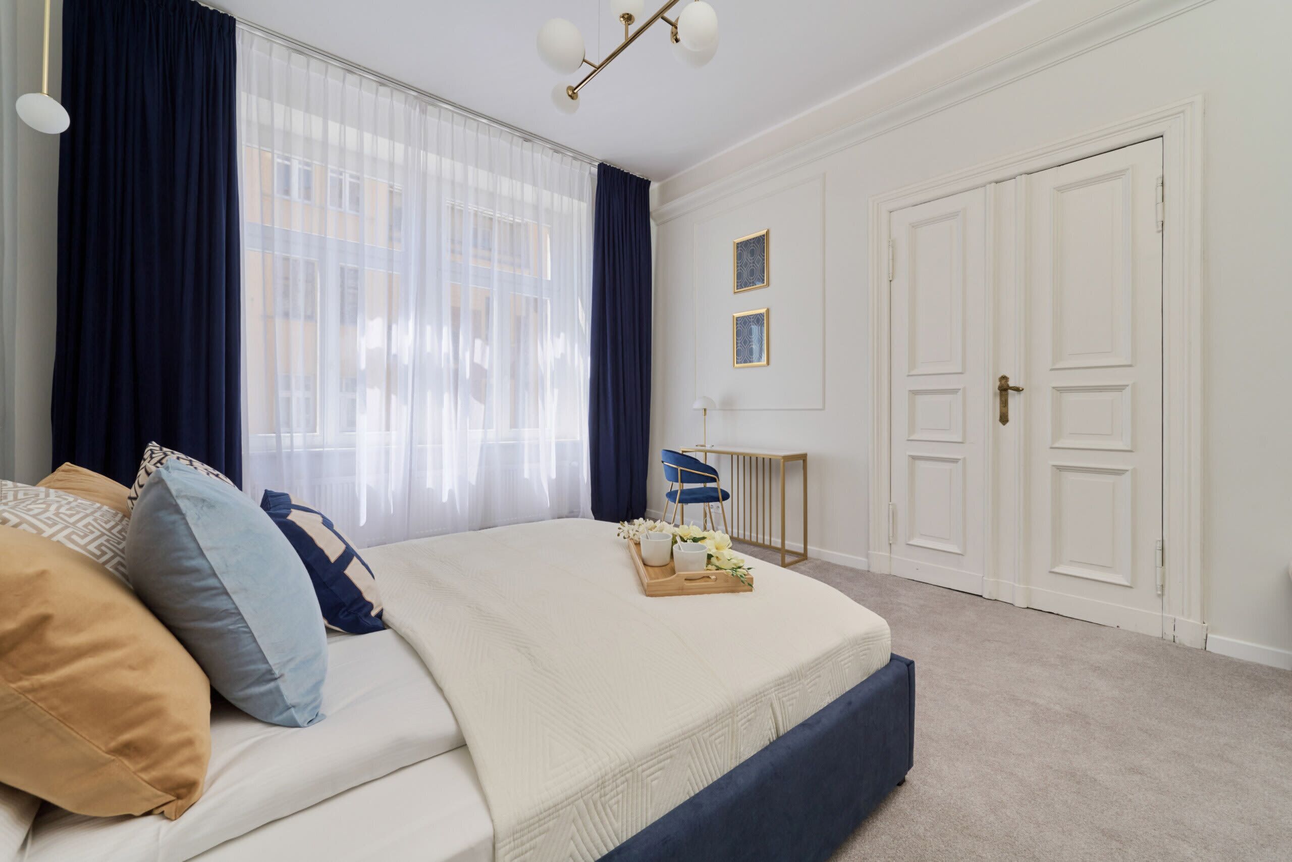 Ein Schlafzimmer mit Bett, Nachttisch, Sessel und Tür.