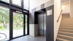 Un interior moderno con una escalera, una puerta con el letrero 'P' y vistas a espacios verdes al exterior.