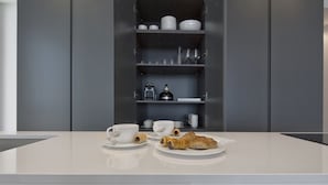 A modern kitchen with a central island, built-in shelves, and recessed lighting. - Luxury Suites Collection-Viale Milano 3 (Riccione)