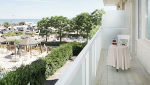 A balcony with a table set for two, overlooking a landscaped outdoor area with seating and a view of the sea. - Luxury Suites Collection-Viale Milano 3 (Riccione)