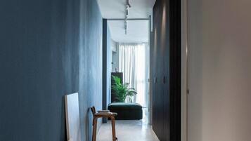 A hallway with a blue wall, a wooden chair, and a door at the end.