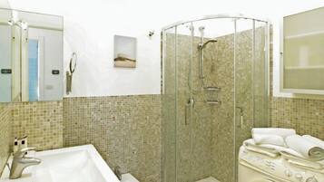 Un baño con lavamanos, inodoro, ducha y lavadora.