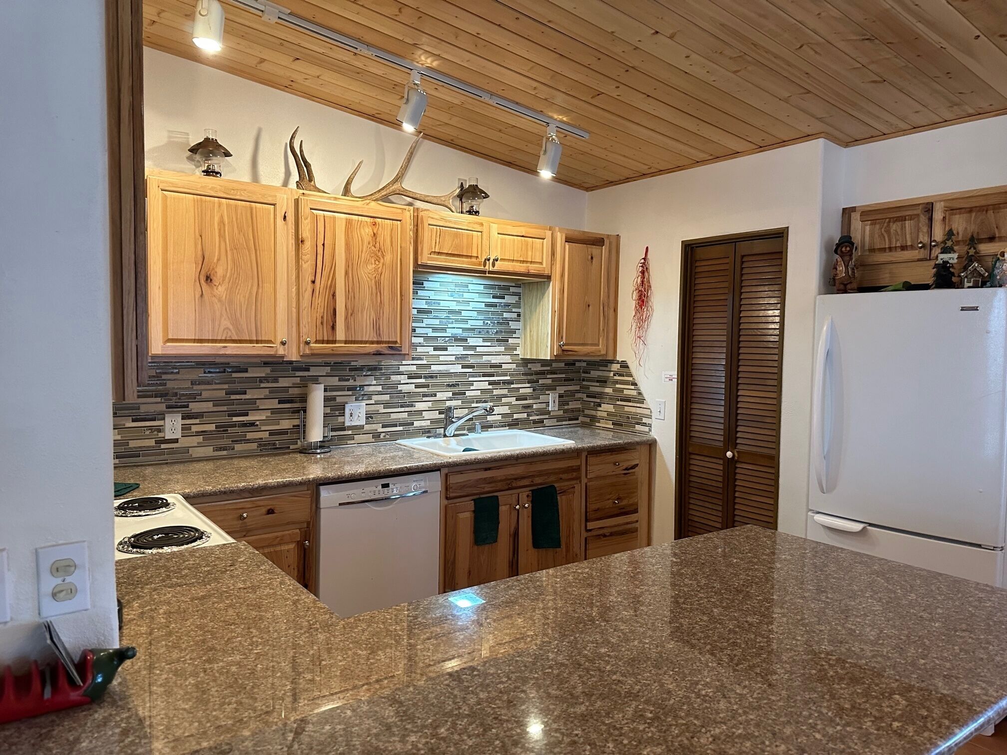 Una cocina con armarios de madera, encimera de granito, salpicadero de azulejos y horno empotrado.