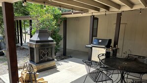 Une terrasse extérieure équipée d’un barbecue, de sièges et d’un foyer.