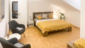 Une chambre à coucher avec un lit, deux chaises, une table de chevet et une petite table.