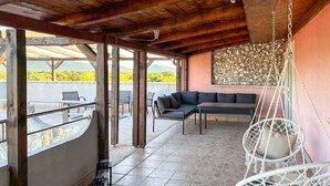 Un espace extérieur abrité, doté d’un plafond en bois, d’un mur en mosaïque et d’un fauteuil suspendu.