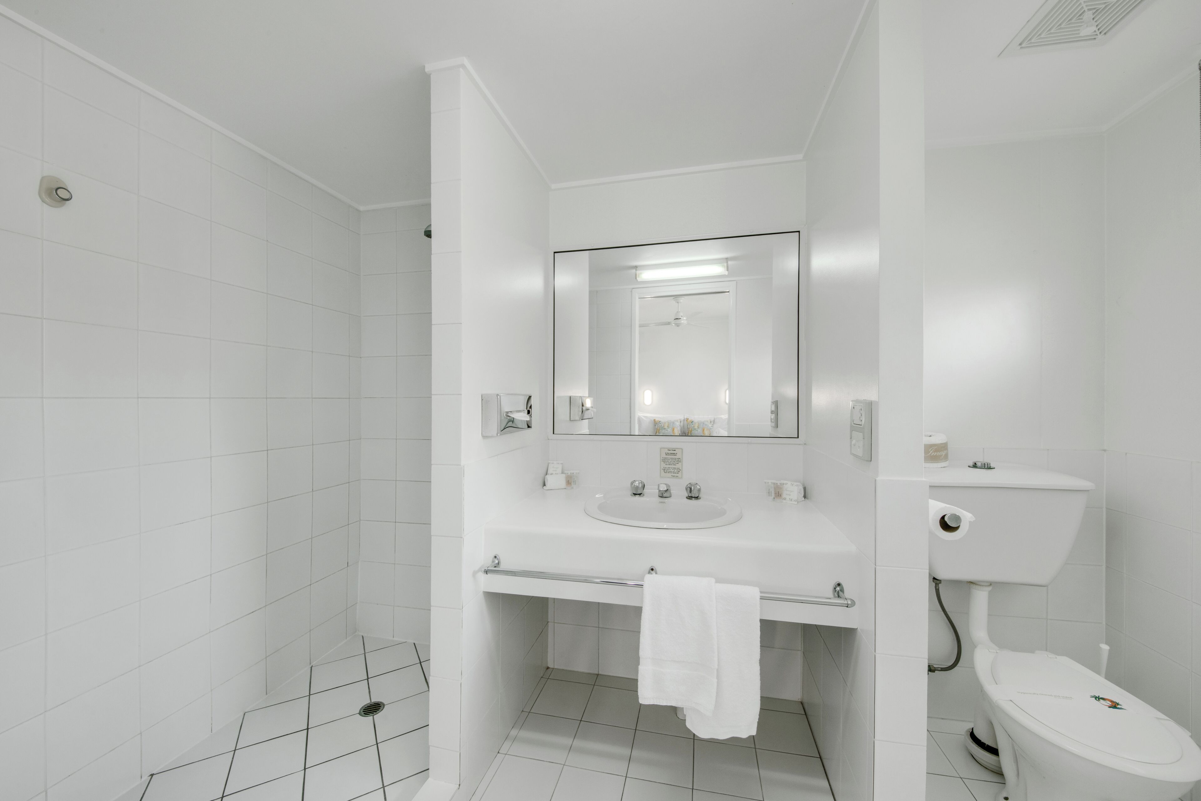 Un baño moderno con azulejos blancos, un lavabo, un inodoro y una zona de ducha.
