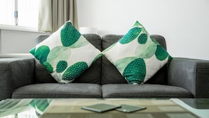 A grey sofa with two decorative pillows featuring a green leaf pattern. - Reef Adventureland Motel (Tannum Sands)
