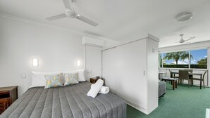 A bedroom with a bed, bedside tables, a desk, and chairs. - Reef Adventureland Motel (Tannum Sands)