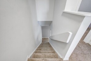 Eine schmale Treppe mit Teppichstufen und weißen Wänden.