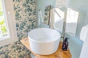 A bathroom with a large white sink, a mirror, and a floral wallpaper. - Cozy recently renovated apartment nestled in the historic center (Savignano sul Rubicone)
