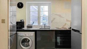 Une cuisine compacte équipée d’un lave-linge, d’une cuisinière et d’un réfrigérateur.
