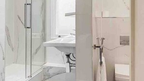 Une salle de bain moderne avec une douche à parois de verre, un lavabo blanc et des toilettes.
