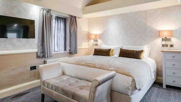 A hotel room with a large bed, a seating area, and a TV mounted on the wall.
