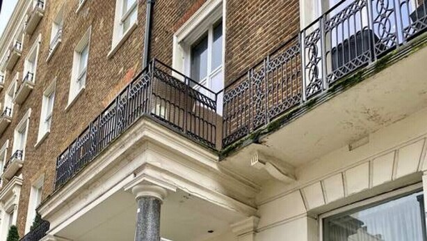 A building with a classical architectural style, featuring a prominent entrance with columns, a balcony with ornate metal railings, and a white facade. - 2 Bed/2 Bath Large Flat, Ground Floor, Sky TV, AC (Greater London)